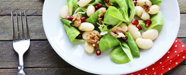 Salat mit Feldsalat, weißen Bohnen, Walnüssen und Granatapfelkernen auf einem Teller